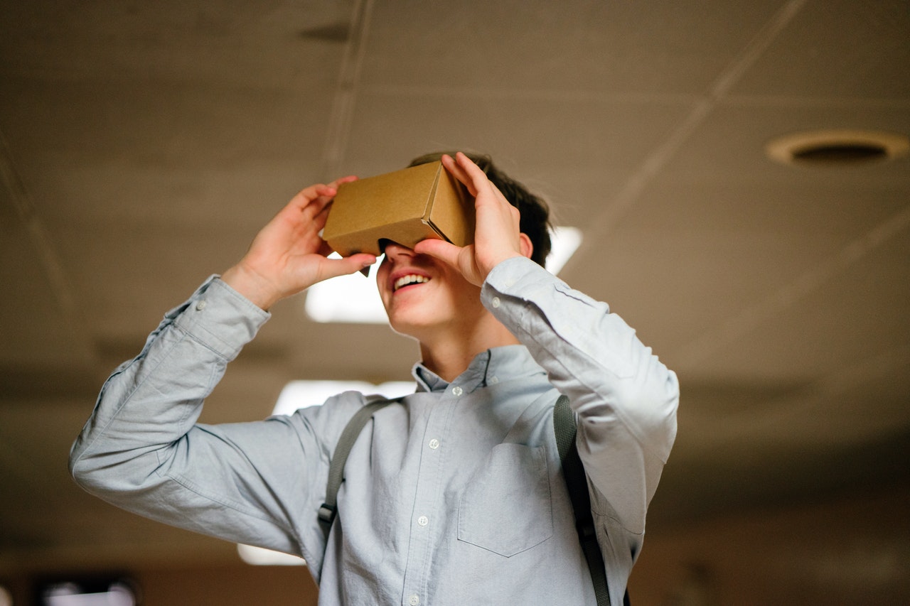 Man in grey shirt holding a cardbox vr headset